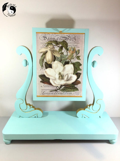 Dixie Belle Paint The Gulf Chalk Mineral Paint is the perfect paint for any DIY project!  A blue chalk painted picture stand holding a printed picture of a white flower.