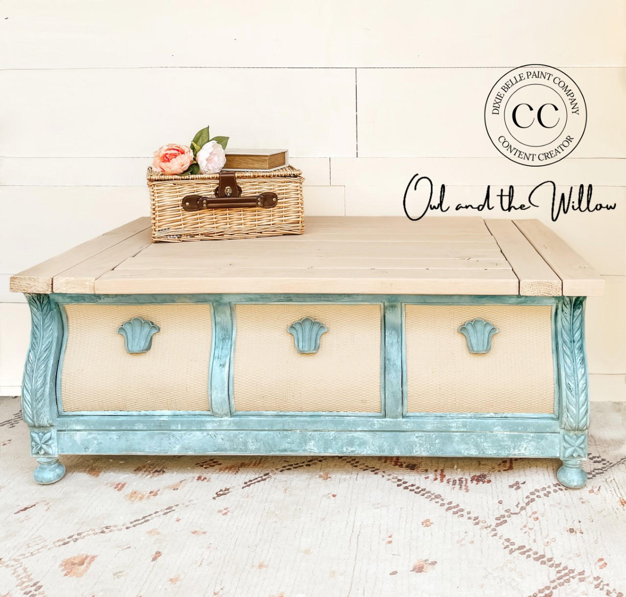 Dixie Belle Paint Vintage Duck Egg Chalk Mineral Paint is the perfect paint for any DIY project!  A square coffee table chalk painted off-white and bluish green sits on a white & brown carpet in front of a white wall.  A tan basket with a dark brown handle sits on top of the table with two light colored flowers and a light colored book with gold pages on top of the basket.