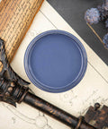 Dixie Belle Paint Yankee Blue Chalk Mineral Paint is the perfect paint for any DIY project!  Top view of an open can of Yankee Blue chalk Mineral Paint on a white sheet of paper with pencil drawings sitting on a black table.  Blue chalk painted mini pinecones sit to the right of the jar on brown sticks.  A bronze antique ke sits on a brown rolled up scroll of paper with handwritten words.