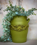 Large green painted pot makeover containing faux greenery.