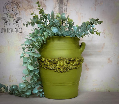 Large green painted pot makeover containing faux greenery.