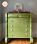 Green painted dresser transformation with white knobs. Staged with faux cranberries and a candle on top. White wreath hanging on the wall behind the piece.