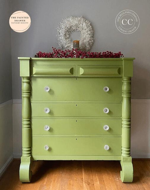 Green painted dresser transformation with white knobs. Staged with faux cranberries and a candle on top. White wreath hanging on the wall behind the piece.