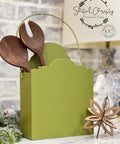 Green painted magazine holder transformation with two wooden spoons inside.