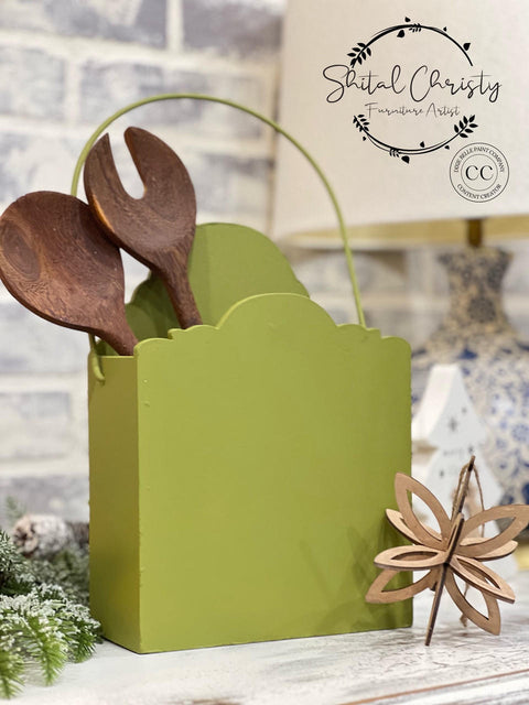 Green painted magazine holder transformation with two wooden spoons inside.