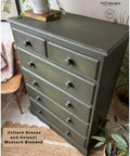 A tall green dresser with six drawers, with a slightly distressed finish. It's surrounded by plants and decor, including a woven chair and a patterned blanket. Text on the image reads "Collard Greens and Colonel Mustard Blended."