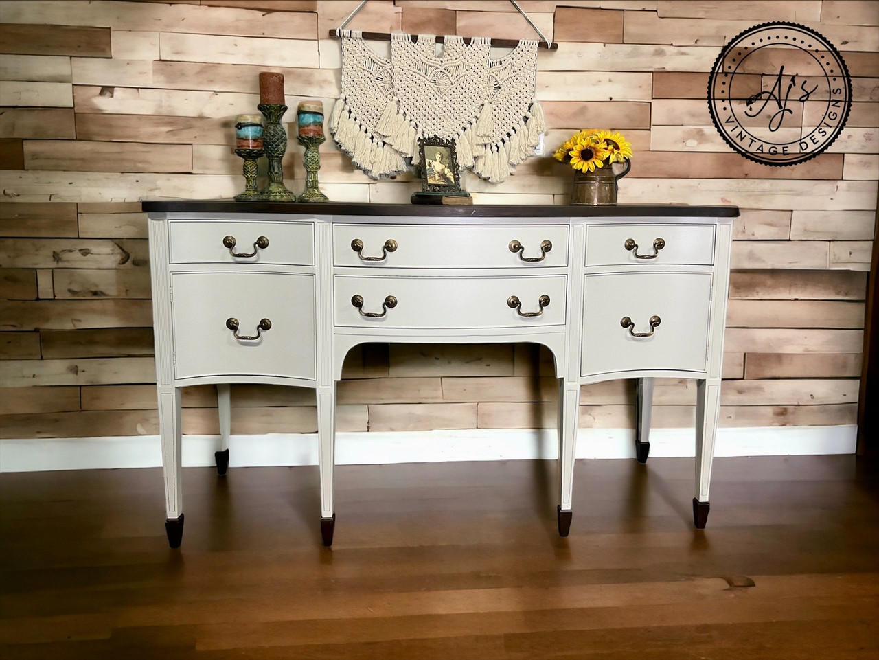 Grayish white painted dresser makeover with dark brown feet and top and bronze pulls. Staged with candlesticks, a picture frame and sunflowers on top.