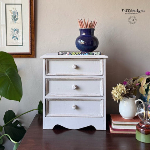 Grayish white painted jewelry box transformation. Staged with a colorful notebook and a blue vase full of pencils on top.