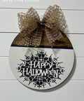 Half natural wood, half white painted circular sign with the spiderweb Happy Halloween Stencil design applied in black. Burlap bow on the top of the sign.