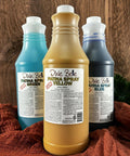 Image of Yellow, Green, and Blue 32 oz. Patina Spray Refills. Staged on an orange blanket with faux greenery and faux wood behind it.