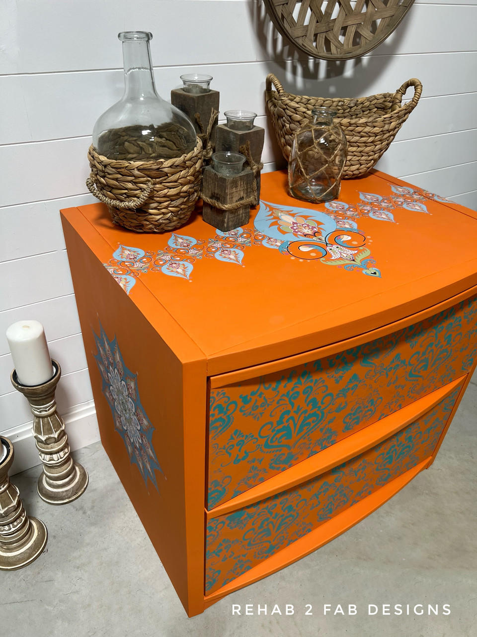 An orange Nightstand table with the Kaleidoscope Transfer applied to the top of the table and on the side. Staged with woven basket and glass jars on top of the piece.