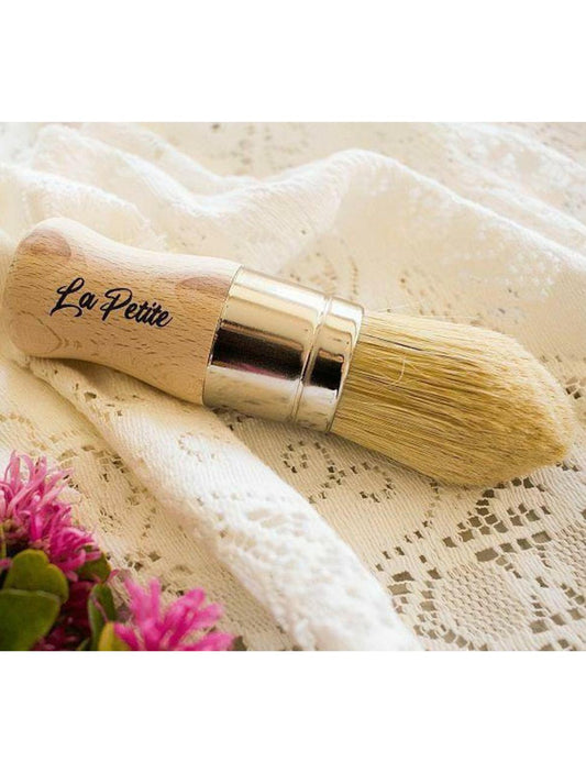 Belles and Whistles La Petite Brush is excellent for detailing and highlighting your project. La Petite Brush on a white lace cloth and flowers off to the side.