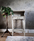 A vintage, white wooden console table, with the Lemon Zest Transfer applied on the drawer, stands against a textured grey wall, accompanied by a potted green plant on an ornate wooden stand and a decorative rug beneath.