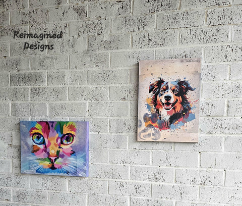 Two colorful animal portraits hang on a white textured brick wall. The left painting depicts a vibrant, abstract cat in shades of purple, blue, pink, and green. The right painting features a lively, multicolored dog. A "Reimagined Designs" logo is on the upper left corner.