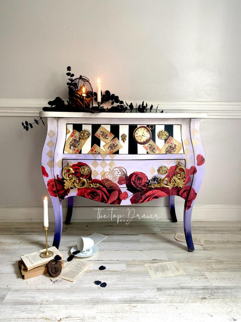 White, black, and purple chalk painted nightstand. The top drawer has been painted with white and black stripes. The Roses are Red Transfer has been applied to the front of the nightstand and on the two drawers. The Harlequin Stencil has been applied in gold.