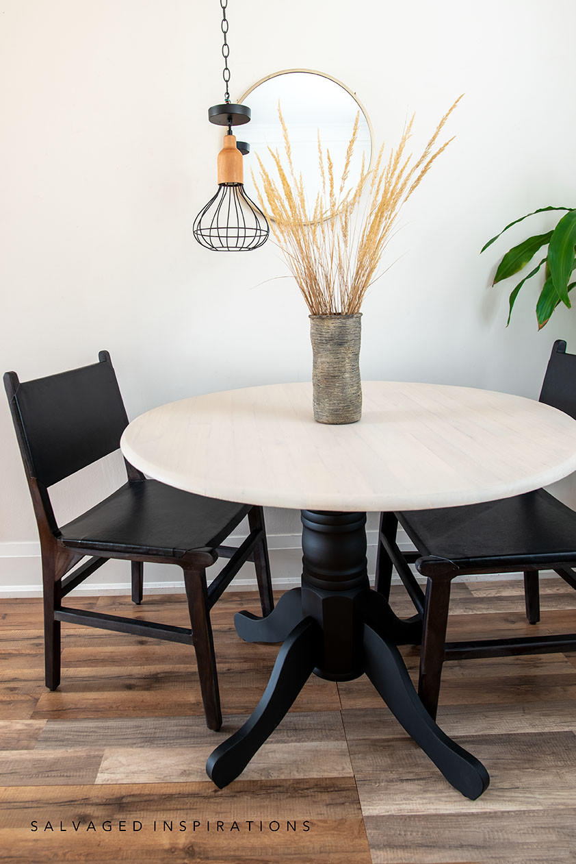 Anchor Silk All-In-One paint is perfect for painting kitchen cabinets, bathroom cabinets and painting furniture. Classic natural wood kitchen dining table. The base and chairs are painted with Anchor Silk All-In-One Mineral Paint. The piece is staged against a white wall with a round mirror and flower arrangement on table.