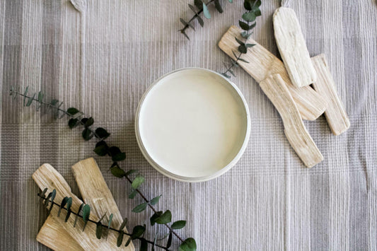 Baja Gray Silk All-In-One Mineral Paint is perfect for painting kitchen cabinets, bathroom cabinets and painting furniture. Image shows a top view of an opened container of  Baja Gray Silk All-In-One Mineral Paint staged on a plaid tablecloth with sticks of palo santo and green branches.