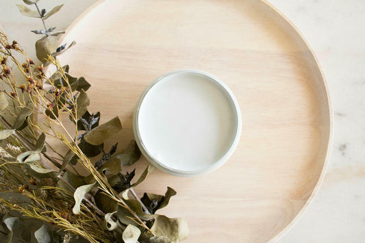Bay Breeze Silk All-In-One paint is perfect for painting kitchen cabinets, bathroom cabinets and painting furniture. 
Image shows a top view of an opened container of  Bay Breeze Silk Paint Staged onto of shallow wooden bowl with some greenery places in the corner.