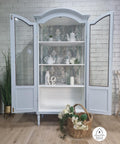 Bay Breeze Silk All-In-One paint is perfect for painting kitchen cabinets, bathroom cabinets and painting furniture.
Image of a beautiful Bay Breeze Silk Paint painted china cabinet displayed with doors wide open and tea pots with tea cups. A woven basket with white flowers is placed Infront of  piece.