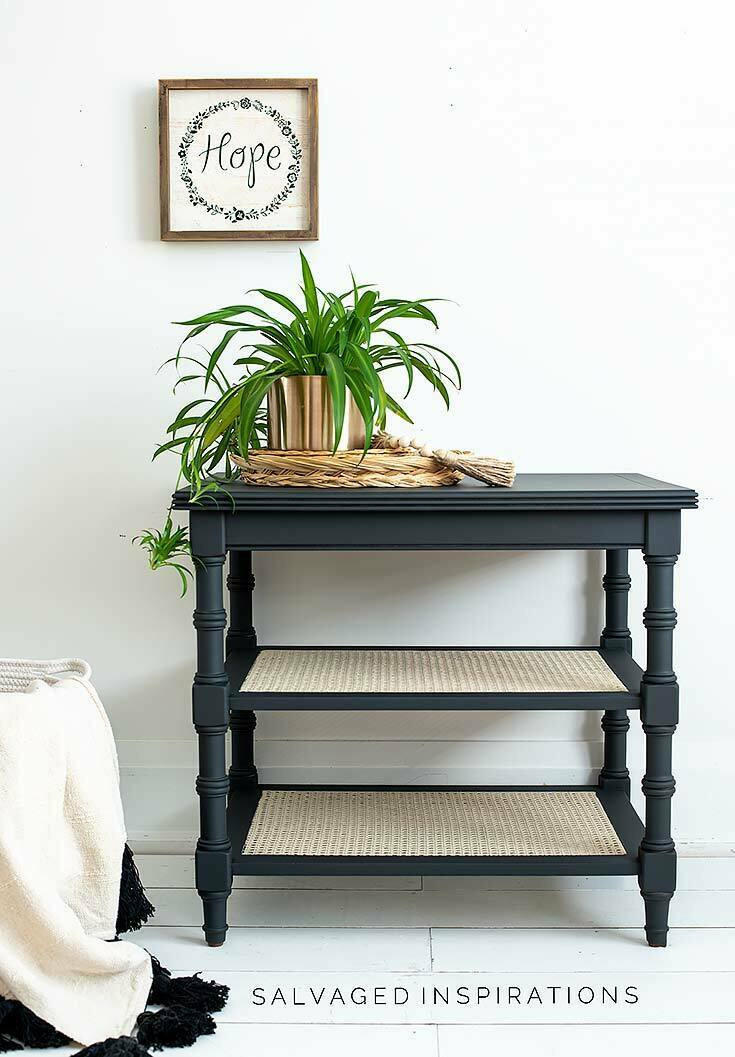 Black Sands Silk All-In-One paint is perfect for painting kitchen cabinets, bathroom cabinets and painting furniture. Entry table with two white rattan shelves below Painted with Black Sand Silk all in one mineral paint. Staged in white walled room with gold planter with faux air plants hanging out and off furniture in a woven basket.