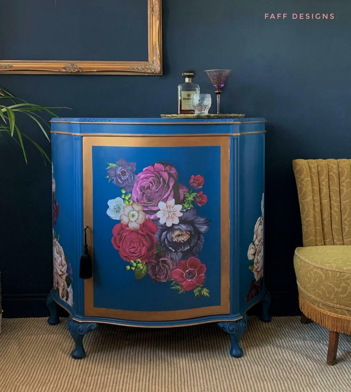 Cape Current Silk All-In-One paint is perfect for painting kitchen cabinets, bathroom cabinets and painting furniture.
A furniture makeover of a bar in Cape Current Silk All-In-One Mineral Paint with a floral design on the front panel with gold border on the door. Staged with a tray,cups and bottle on top of the bar.