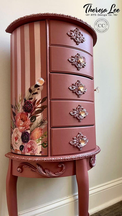 Desert Rose Silk All-In-One paint is perfect for painting kitchen cabinets, bathroom cabinets and painting furniture
Here is a large, tall, 5 drawered, three-legged jewelry piece of furniture.  It is painted in Desert Rose CMP.  There are appliques on the bottom of the furniture and Decoupage on side of the piece.  The side is painted in stripes with Desert Rose alternating with Soft Pink CMP.  This piece of furniture is up against a light green wall.