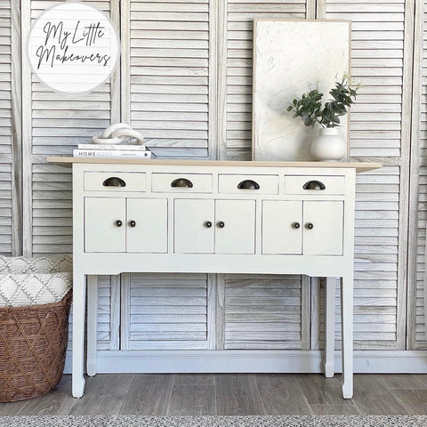 Endless Shore Silk All-In-One paint is perfect for painting kitchen cabinets, bathroom cabinets and painting furniture. White painted table makeover with black handles and a natural wood top. Staged with 2 white books on top and a white vase with faux greenery inside.