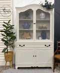 Endless Shore Silk All-In-One paint is perfect for painting kitchen cabinets, bathroom cabinets and painting furniture. White painted armoire with black handles. Styled next to a woven planter containing faux greenery. Wooden chair placed on the right of the armoire.