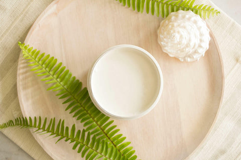 Endless Shore Silk All-In-One paint is perfect for painting kitchen cabinets, bathroom cabinets and painting furniture. Open jar of Endless Shore Silk paint placed on a wooden board with a white sea shell and faux greenery.