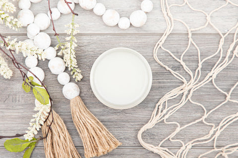 Silk All-In-One Mineral Paint Extra Coat. Open jar of Extra Coat next to faux greenery, wooden beads with yarn on the ends, and a fabric net placed around it.