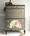 Hampton Olive Silk All-In-One paint is perfect for painting kitchen cabinets, bathroom cabinets and painting furniture.
A chest of drawers painted in Hampton Olive Silk All-In-One paint with gold hardware. A painting of a woman in a semicircle is seen on the bottom half of the piece.
