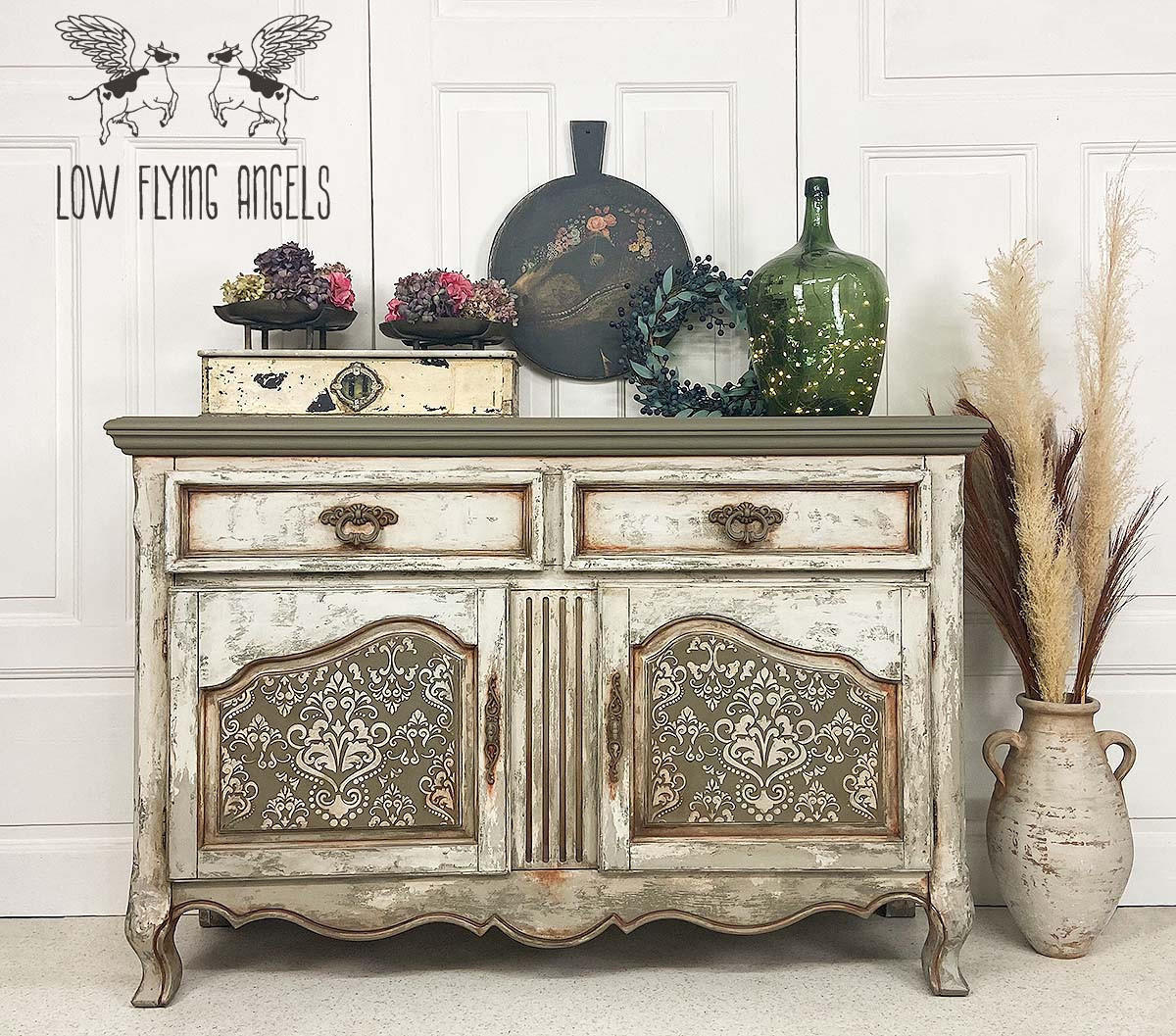 Hampton Olive Silk All-In-One paint is perfect for painting kitchen cabinets, bathroom cabinets and painting furniture.
Credenza with a white farmhouse distressed look, on both door panels its painted with Hampton Olive Silk All-In-One paint along with the Victorian Damask - Stencil in white on top of the Hampton Olive.