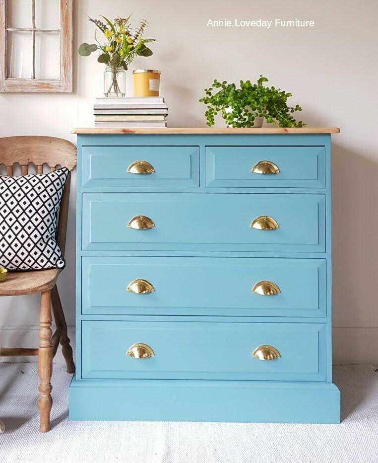 Harbor Silk All-In-One paint is perfect for painting kitchen cabinets, bathroom cabinets and painting furniture.
Chest of drawers painted in Harbor Silk All-In-One paint with gold hardware, staged on top of the piece are books stacked on eachother with candle and potted plants. A wooden chair with a white and black pillow on top is seen on the left side of the piece.