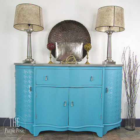 Harbor Silk All-In-One paint is perfect for painting kitchen cabinets, bathroom cabinets and painting furniture.
Entertainment center painted in Harbor Silk All-In-One paint with silver hardware. Staged with two silver lamps on the top of the piece and a brown round decor in the center.