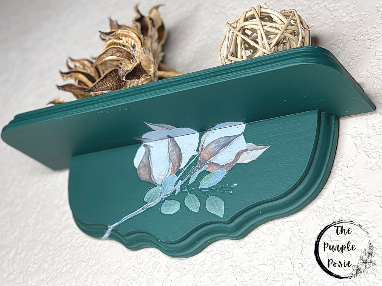 Midnight Green Silk All-In-One paint is perfect for painting kitchen cabinets, bathroom cabinets and painting furniture. Dark green wall Shelf with Floral Rub on transfer. Staged with a wicker ball and a dried up plant.