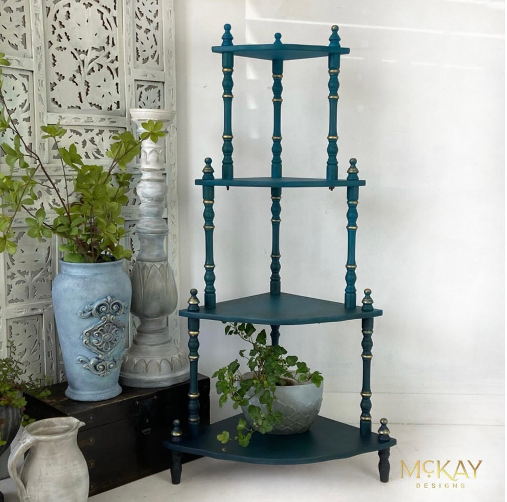 Mirage Silk All-In-One paint is perfect for painting kitchen cabinets, bathroom cabinets and painting furniture. Blue Green Silk All-In-One paint plant stand with Gold accents on the legs. Staged with a black trunk and potted plants.