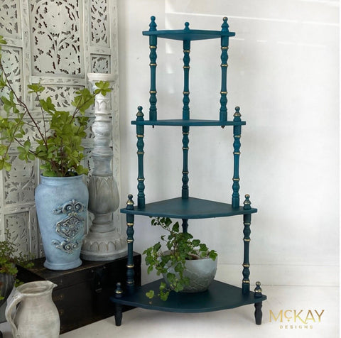 Mirage Silk All-In-One paint is perfect for painting kitchen cabinets, bathroom cabinets and painting furniture. Blue Green Silk All-In-One paint plant stand with Gold accents on the legs. Staged with a black trunk and potted plants.