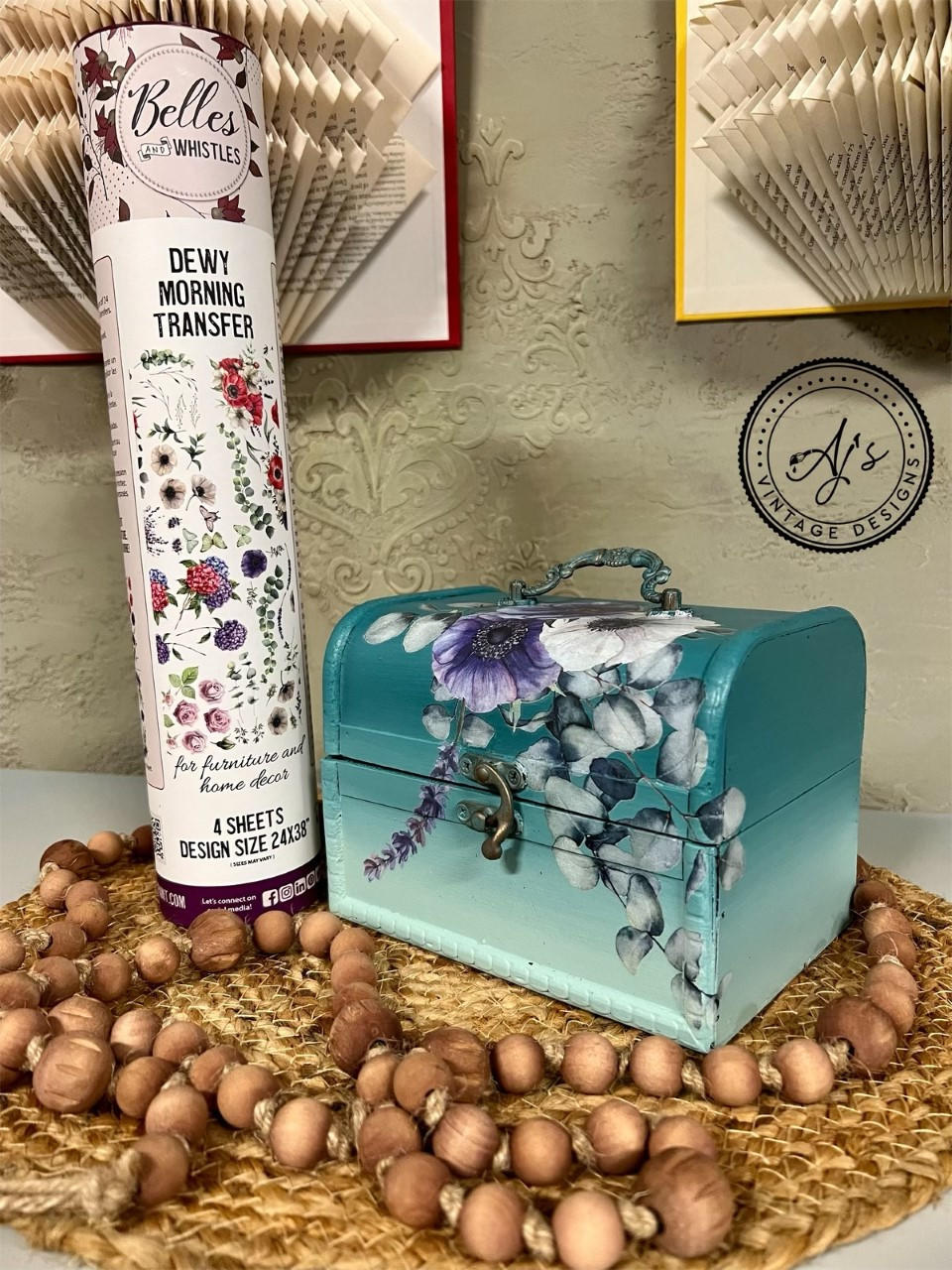 Mirage Silk All-In-One paint is perfect for painting kitchen cabinets, bathroom cabinets and painting furniture. Blue Green Silk All-In-One paint Ombre case with floral rub on transfers. Staged next to a tube of Belles and whistles Dewy Morning transfers, sitting on top of a wicker plate holder and wood beads wrapped around.