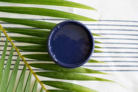 Nautical Silk All-In-One paint is perfect for painting kitchen cabinets, bathroom cabinets and painting furniture. Dark blue open paint can top view sitting on a palm frond.