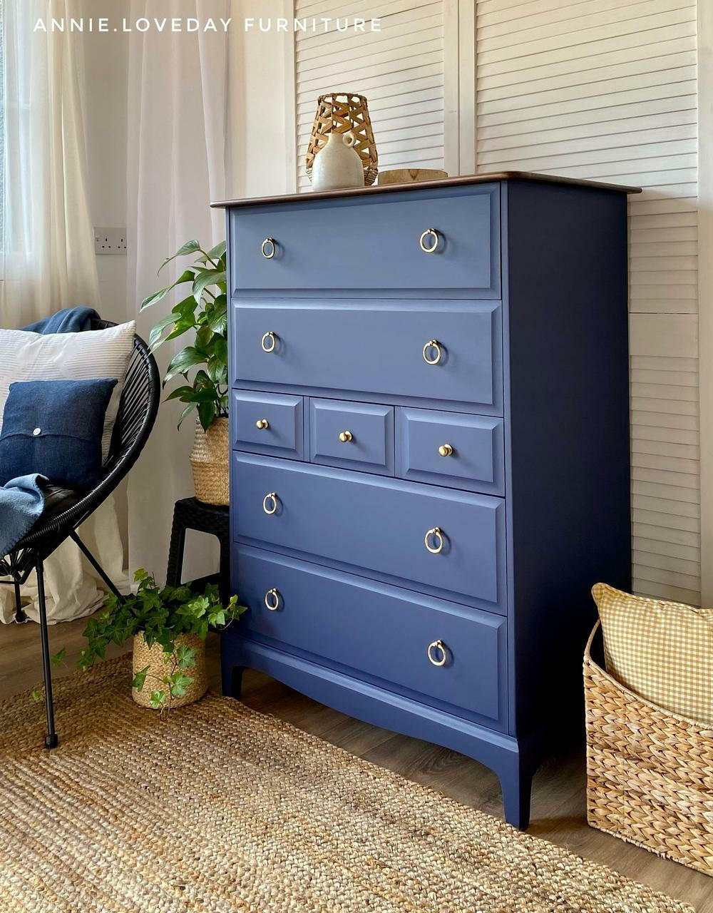 Nautical Silk All-In-One paint is perfect for painting kitchen cabinets, bathroom cabinets and painting furniture. Dark blue painted dresser with gold hard ware. Staged in a bedroom with plants and wicker basket.