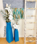 Oasis Silk All-In-One paint is perfect for painting kitchen cabinets, bathroom cabinets and painting furniture. Blue Silk Chalk painted tall flower vases. Staged with white flowers next to a white blanket ladder and a gray blanket on the wall.