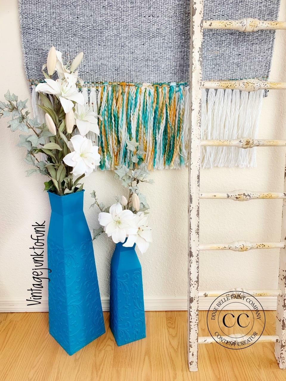 Oasis Silk All-In-One paint is perfect for painting kitchen cabinets, bathroom cabinets and painting furniture. Blue Silk Chalk painted tall flower vases. Staged with white flowers next to a white blanket ladder and a gray blanket on the wall.