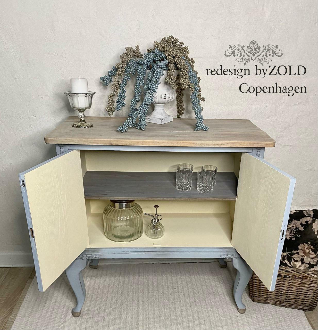 Sun Kissed Silk All-In-One paint is perfect for painting kitchen cabinets, bathroom cabinets and painting furniture.
Open displayed bar with the inside of the bar painted in Sun Kissed Silk All-In-One paint with a natural wood top and gray outside. Staged with glass cups, jar and a ceramic planter with bronze and silver beads.