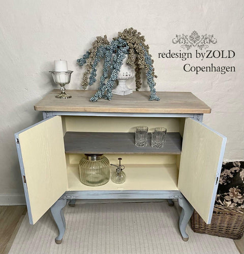 Sun Kissed Silk All-In-One paint is perfect for painting kitchen cabinets, bathroom cabinets and painting furniture.
Open displayed bar with the inside of the bar painted in Sun Kissed Silk All-In-One paint with a natural wood top and gray outside. Staged with glass cups, jar and a ceramic planter with bronze and silver beads.