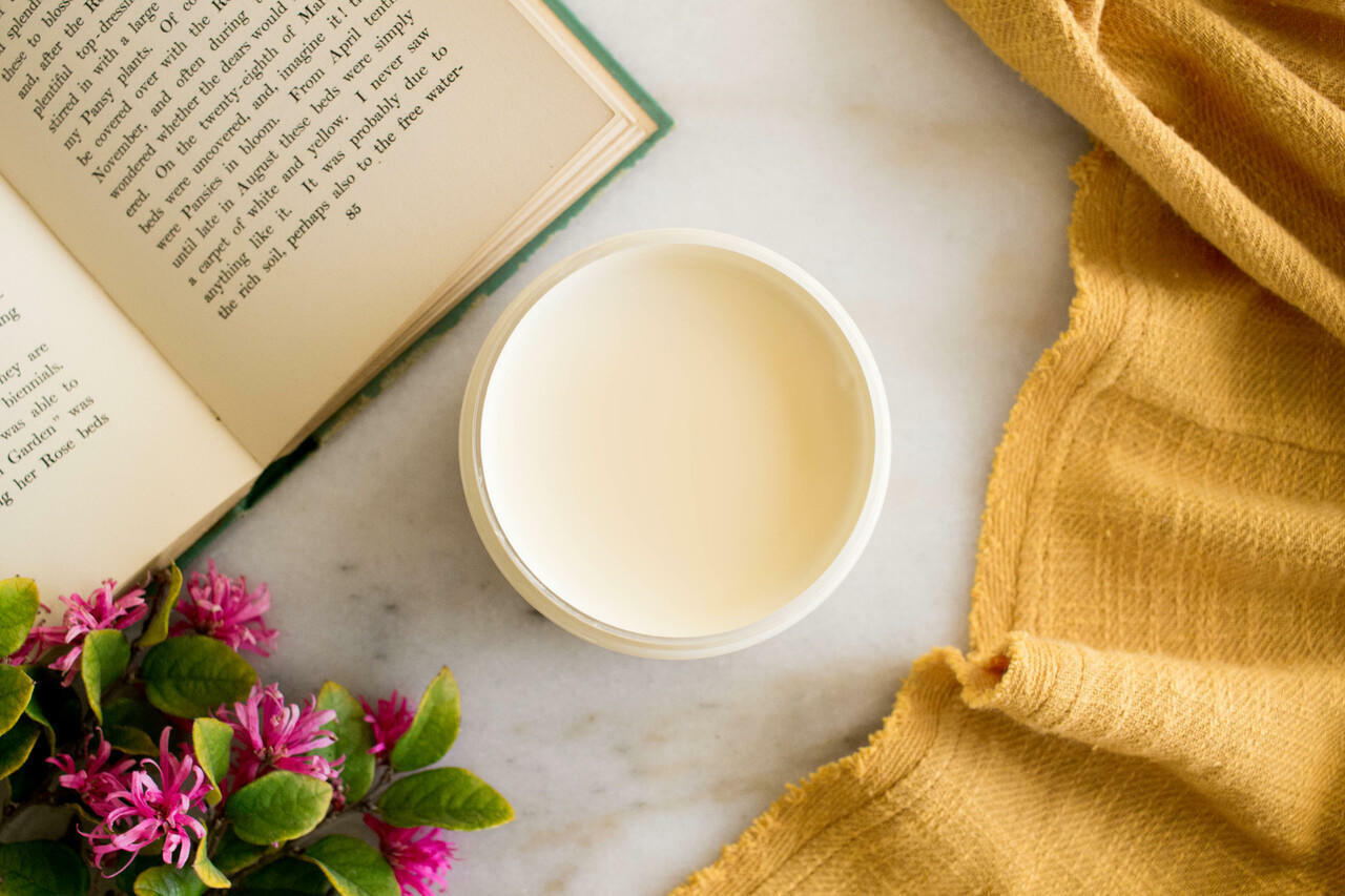 Sun Kissed Silk All-In-One paint is perfect for painting kitchen cabinets, bathroom cabinets and painting furniture.
Opened container of Sun Kissed Silk All-In-One Mineral Paint. Staged with an opened book,flower and a yellow linen.