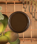 Umber Silk All-In-One paint is perfect for painting kitchen cabinets, bathroom cabinets and painting furniture.  An open jar of Umber Silk All-In-One paint sitting on a copper wire rack with greenery around it.