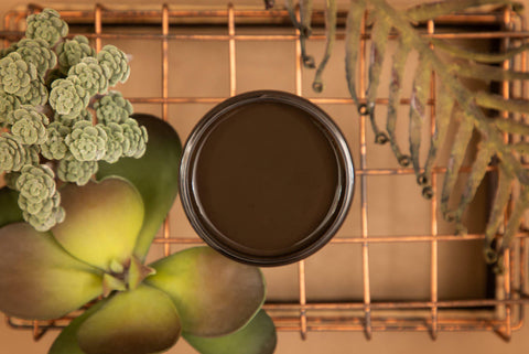 Umber Silk All-In-One paint is perfect for painting kitchen cabinets, bathroom cabinets and painting furniture.  An open jar of Umber Silk All-In-One paint sitting on a copper wire rack with greenery around it.