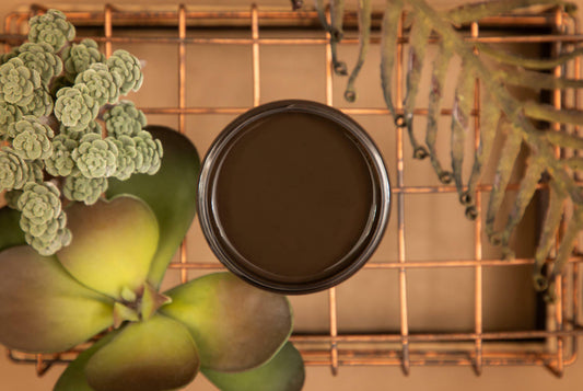Umber Silk All-In-One paint is perfect for painting kitchen cabinets, bathroom cabinets and painting furniture.  An open jar of Umber Silk All-In-One paint sitting on a copper wire rack with greenery around it.