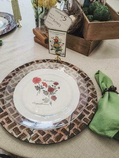 Umber Silk All-In-One paint is perfect for painting kitchen cabinets, bathroom cabinets and painting furniture.  A clear and white glass plate with a flower transfer applied to the center sitting on a place mat with a stencil painted on with Umber Silk All-In-One Mineral Paint.  Sitting on a gold table with a green cloth napkin to the right and brown boxes behind it with a decorative card.