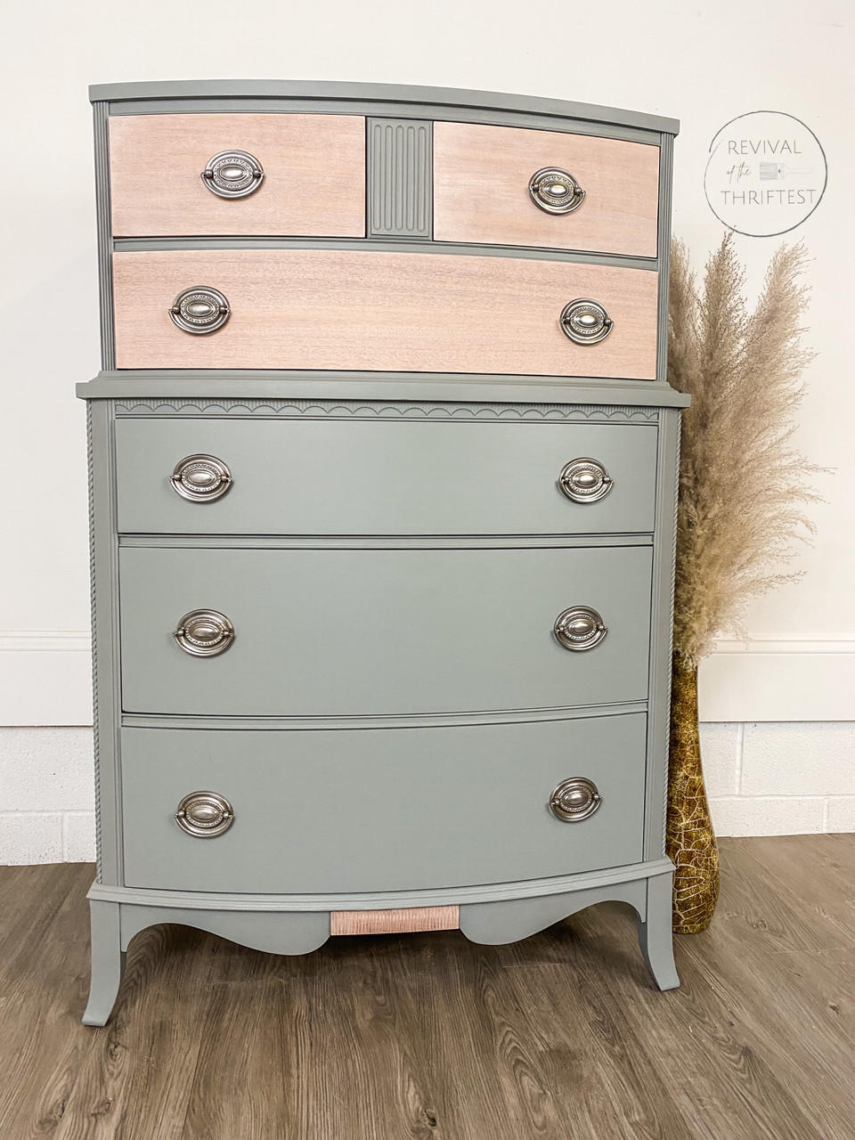 Wharf Silk All-In-One paint that is perfect for painting kitchen cabinets, bathroom cabinets and painting furniture.  A gray and pink chalk painted dresser with silver handles sits on a brown wooden floor, in front of a white wall.  Brown feathers sit inside of a tall brown vase sit on the floor to the right of the dresser.